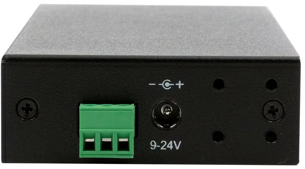 Schwarzes rechteckiges Gerät mit grünem Stecker, Stromeingang und Schraubenköpfen. Markierungen umfassen Plus- und Minuszeichen sowie 9-24V.