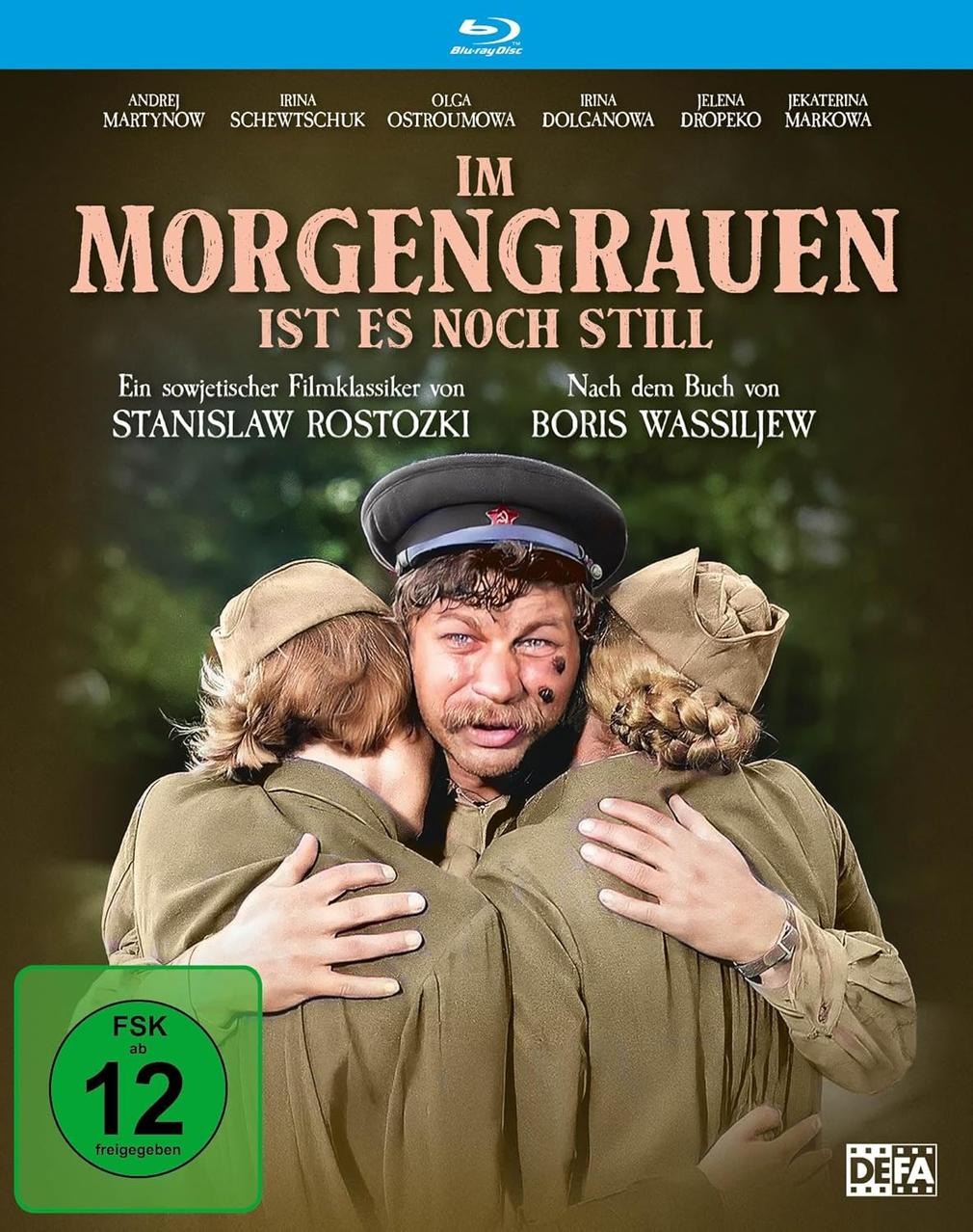 Filmposter. Drei Personen in Uniformen umarmen sich. Der Titel lautet 'Im Morgengrauen'. Grünes Bewertungssiegel unten links.