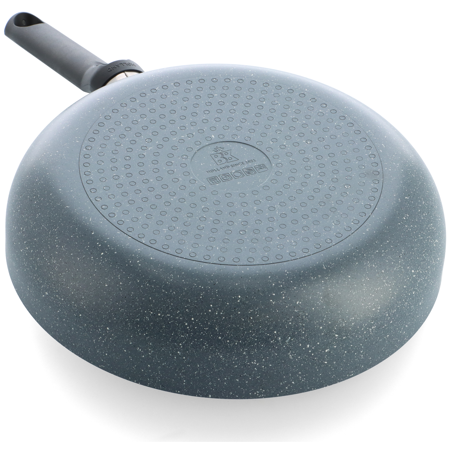 The bottom of a grey speckled wok with a black handle, placed on a white surface. The handle is angled to the left.