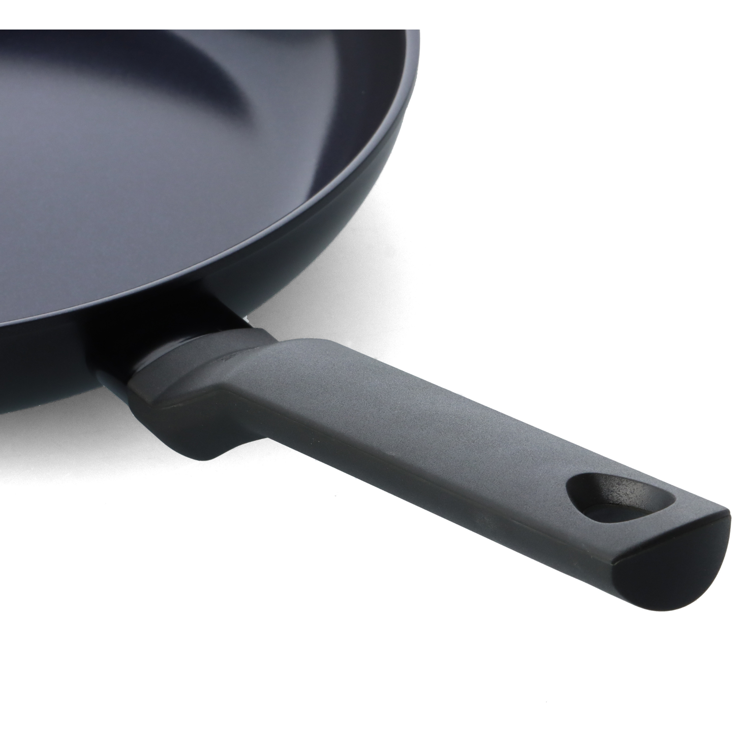 Close-up of a dark grey frying pan with a black handle. The pan is on a white background. The handle has a hole near the end.