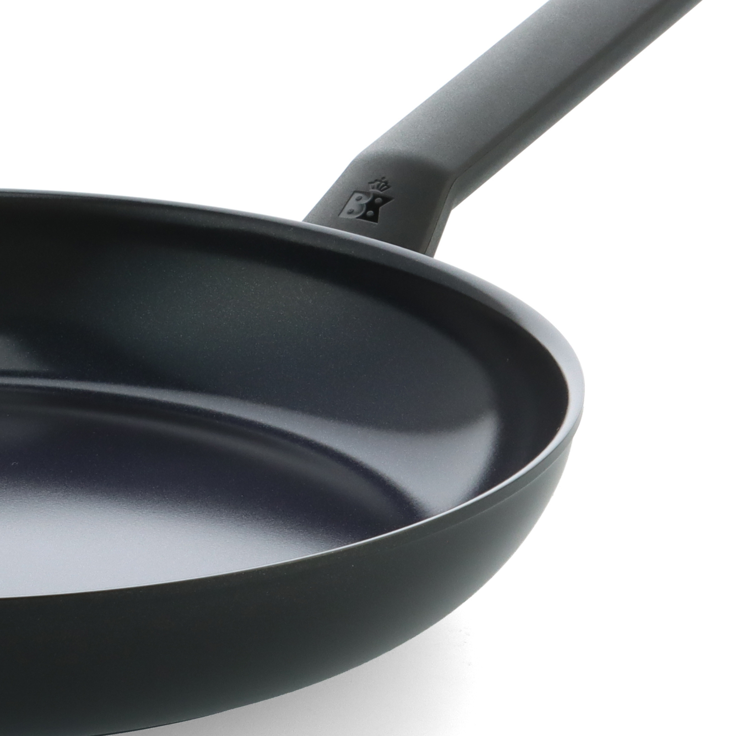 Close-up of a black frying pan with a long handle, the pan is on a white background.