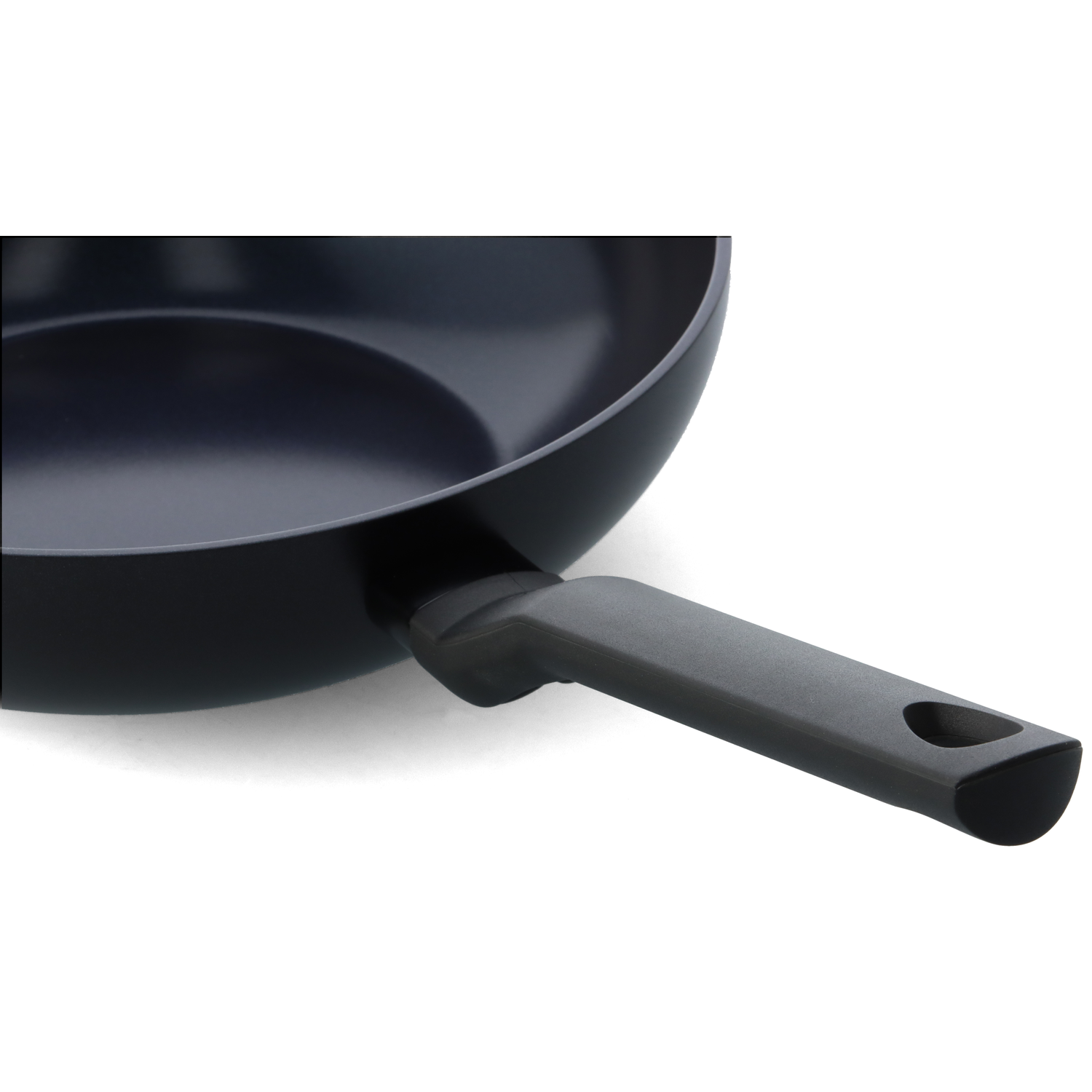 Close-up of a black frying pan with a dark gray handle. The pan is on a white background.