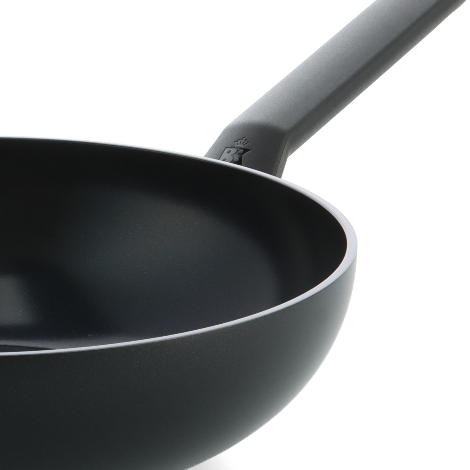 Close-up of a black wok with a gray handle on a white background. The wok is empty and shows a silver rim.