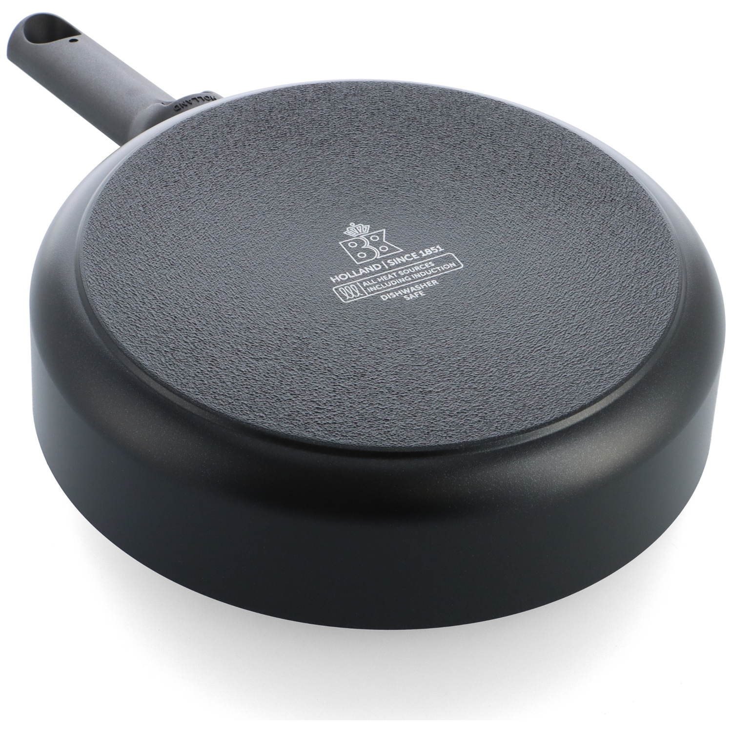 The bottom of a black frying pan is shown. It has a textured surface and a gray handle. The brand logo is visible.