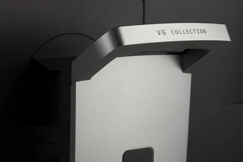 Közeli kép egy fém szerkezetről, rajta a 'VG COLLECTION' felirattal. A háttér sötét.