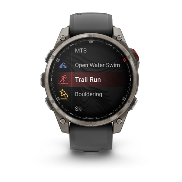 A Garmin okosóra aktivitási lehetőségeket jelenít meg: MTB, Open Water Swim, Trail Run (kiemelve), Bouldering és Ski. Az óra szürke, fekete képernyővel.