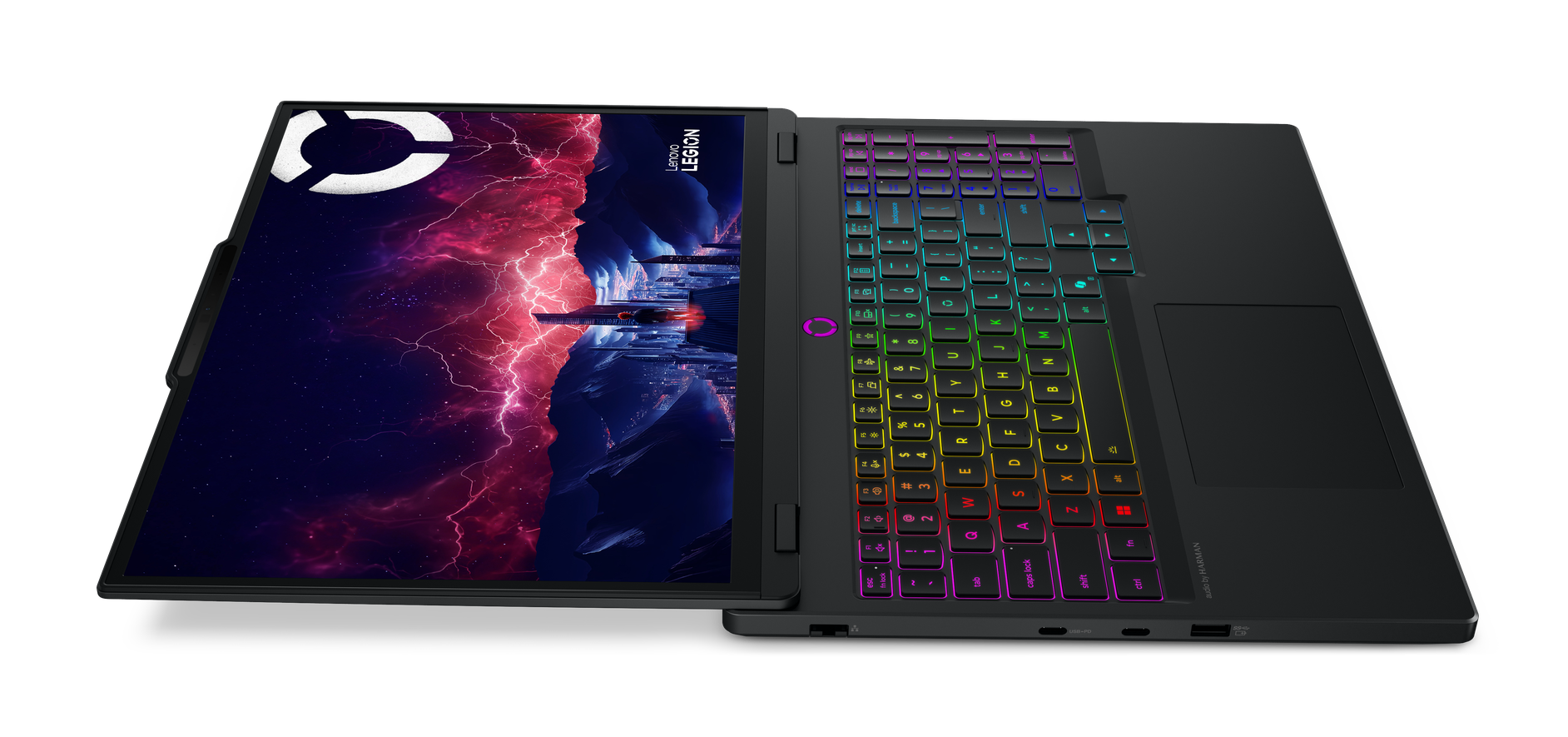 Czarny laptop Lenovo Legion jest otwarty. Ekran pokazuje kolorową scenę fantasy. Klawiatura jest podświetlona tęczowymi kolorami.