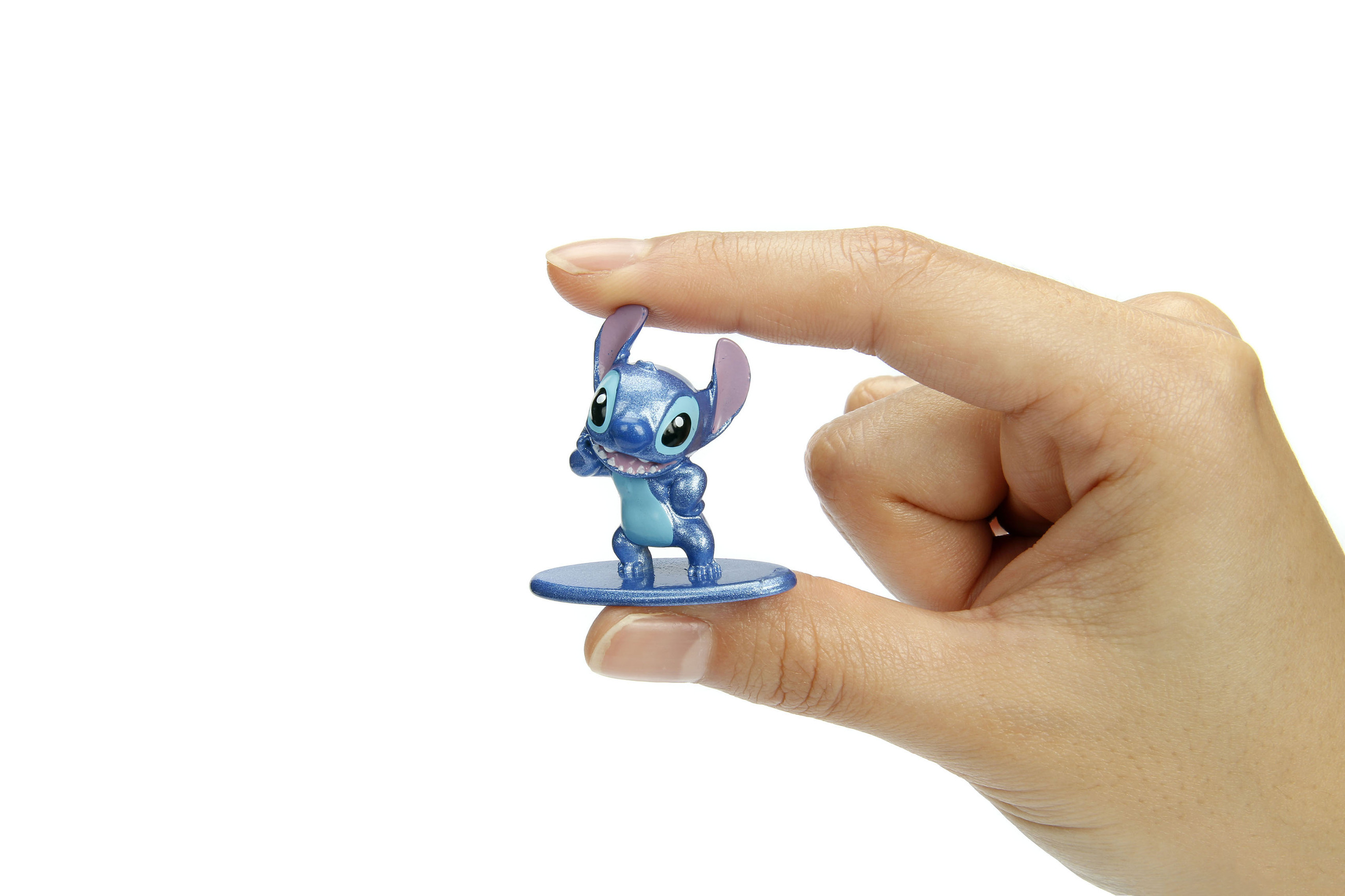 Eine Hand hält eine blaue Stitch-Figur. Stitch steht auf einem blauen Sockel. Weißer Hintergrund.