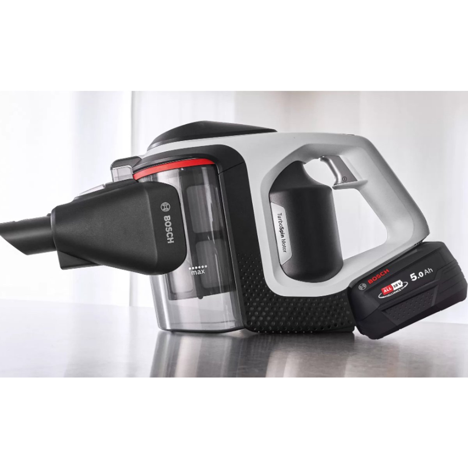 Un aspirateur sans fil Bosch. Il est principalement noir et blanc avec un accent rouge et une batterie.