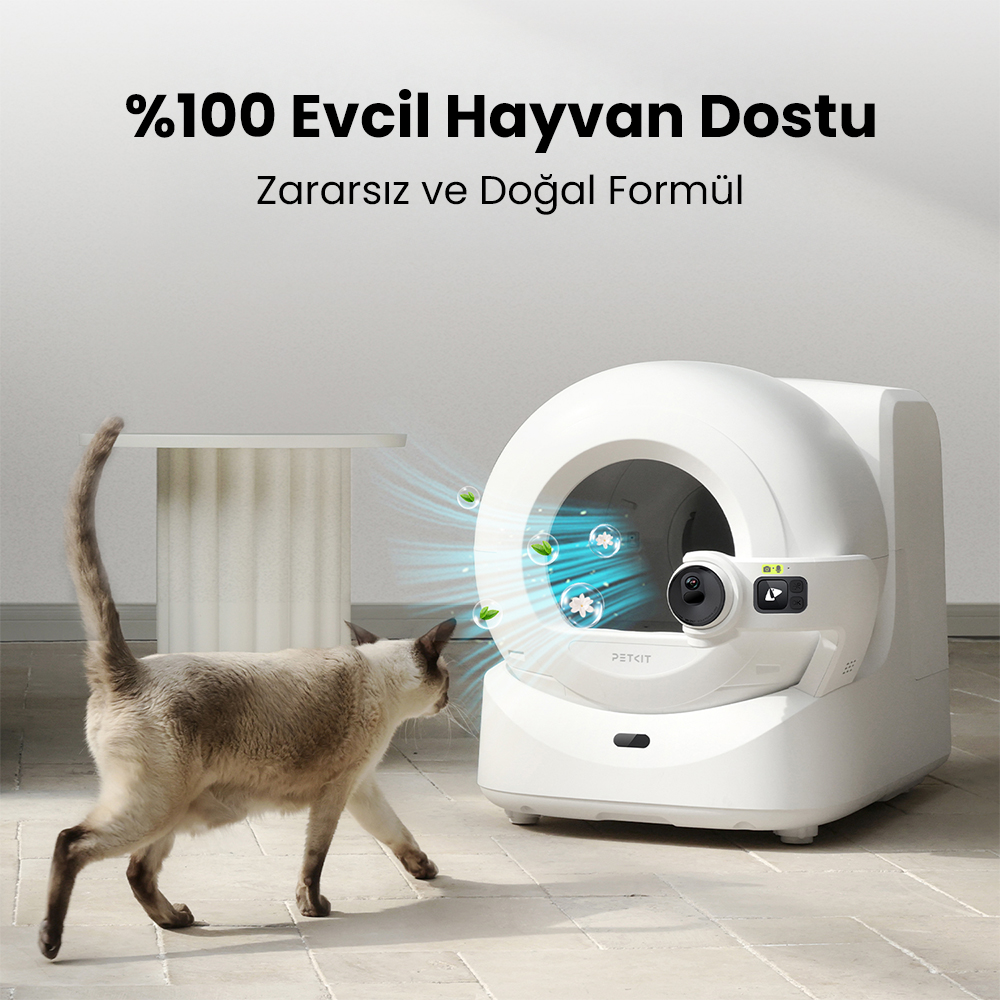 Bir kedi, beyaz otomatik bir kedi tuvaletine doğru yürüyor. Tuvaletin yuvarlak bir girişi var ve üstteki metin '100% evcil hayvan dostu' diyor.