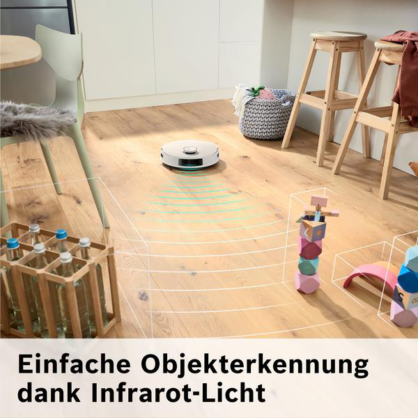 Ein Roboter-Staubsauger auf Holzboden. Spielzeug und Hocker sind im Hintergrund. Der Staubsauger verwendet Infrarotlicht zur Objekterkennung.