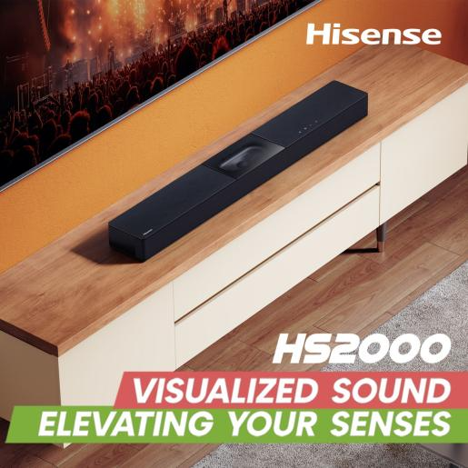 Egy fekete soundbar egy fa szekrényen. A TV egy tömeget mutat. A szöveg: 'Hisense', 'HS2000' és 'Elevating Your Senses'.