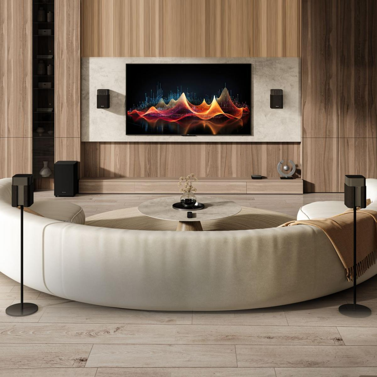 Egy modern nappali, nagy TV-vel, színes grafikával, hangszórókkal, fehér, ívelt kanapéval és dohányzóasztallal.