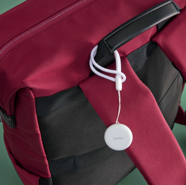 Ein weinroter Rucksack mit einem weißen Ortungsgerät. Das Gerät ist am Riemen befestigt.