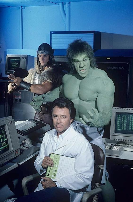 Hulk, Thor und ein Wissenschaftler posieren. Der Hulk ist grün, muskulös und wütend. Thor ist kostümiert. Wissenschaftler hält Papiere.