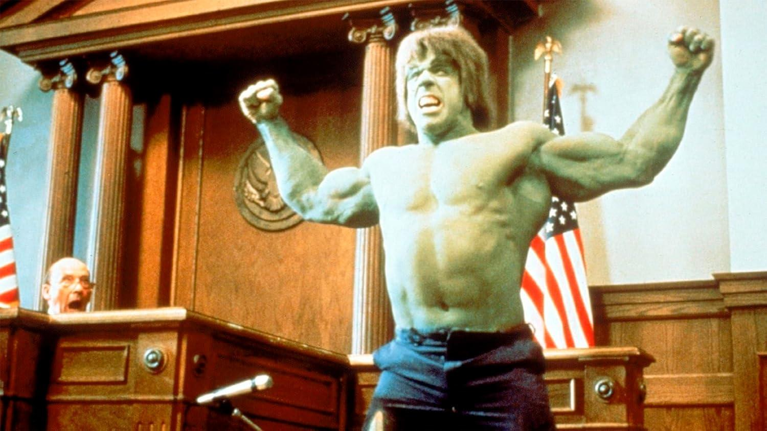Der Hulk im Gerichtssaal, Fäuste erhoben. Amerikanische Flaggen und eine Richterbank sind im Hintergrund. Ein Mann ist sichtbar.