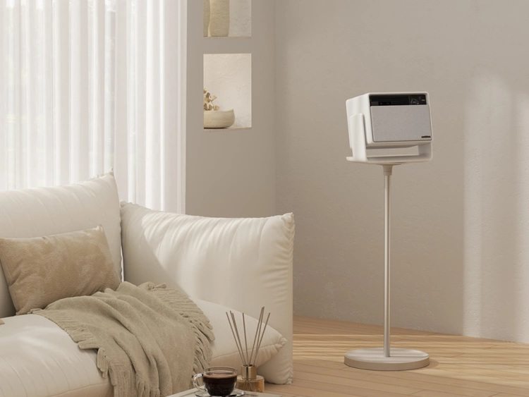 Scena w salonie z białą sofą, kocem i białym głośnikiem na stojaku. Na stole filiżanka kawy i trzciny.