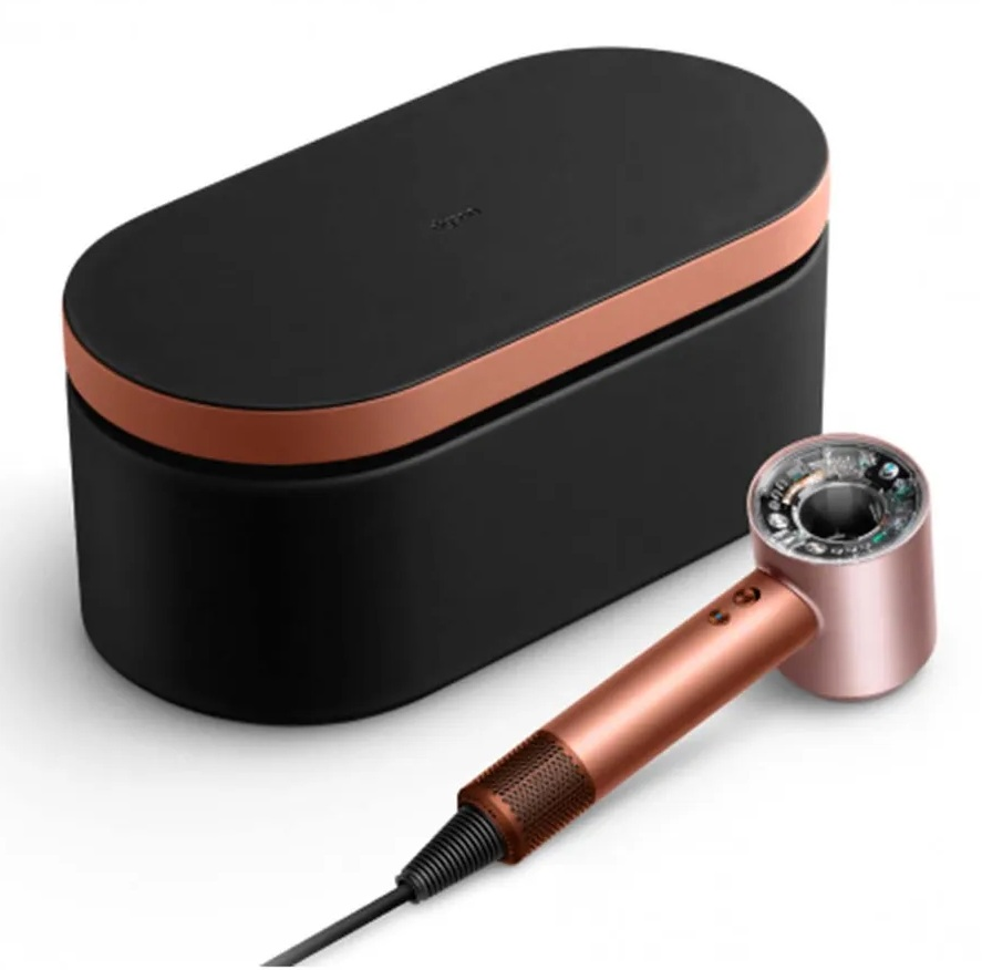 Czarna i miedziana suszarka do włosów Dyson i etui. Suszarka jest miedziana z czarnym kablem. Etui jest czarne z miedzianym paskiem.