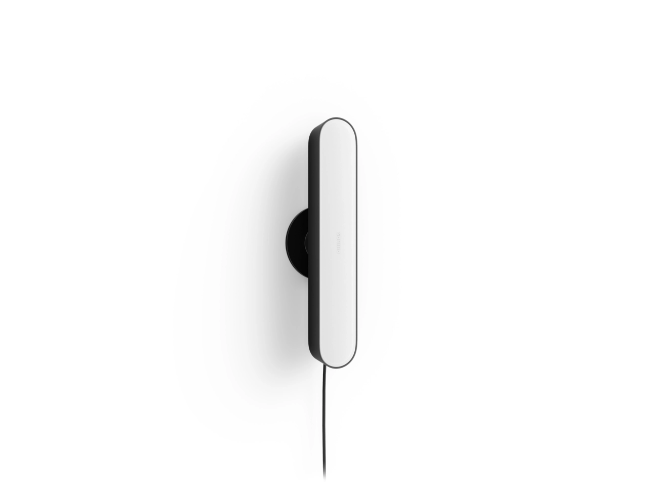 Eine Wandleuchte. Sie ist schwarz und weiß und hat eine abgerundete Rechteckform. Ein schwarzes Kabel hängt herunter.