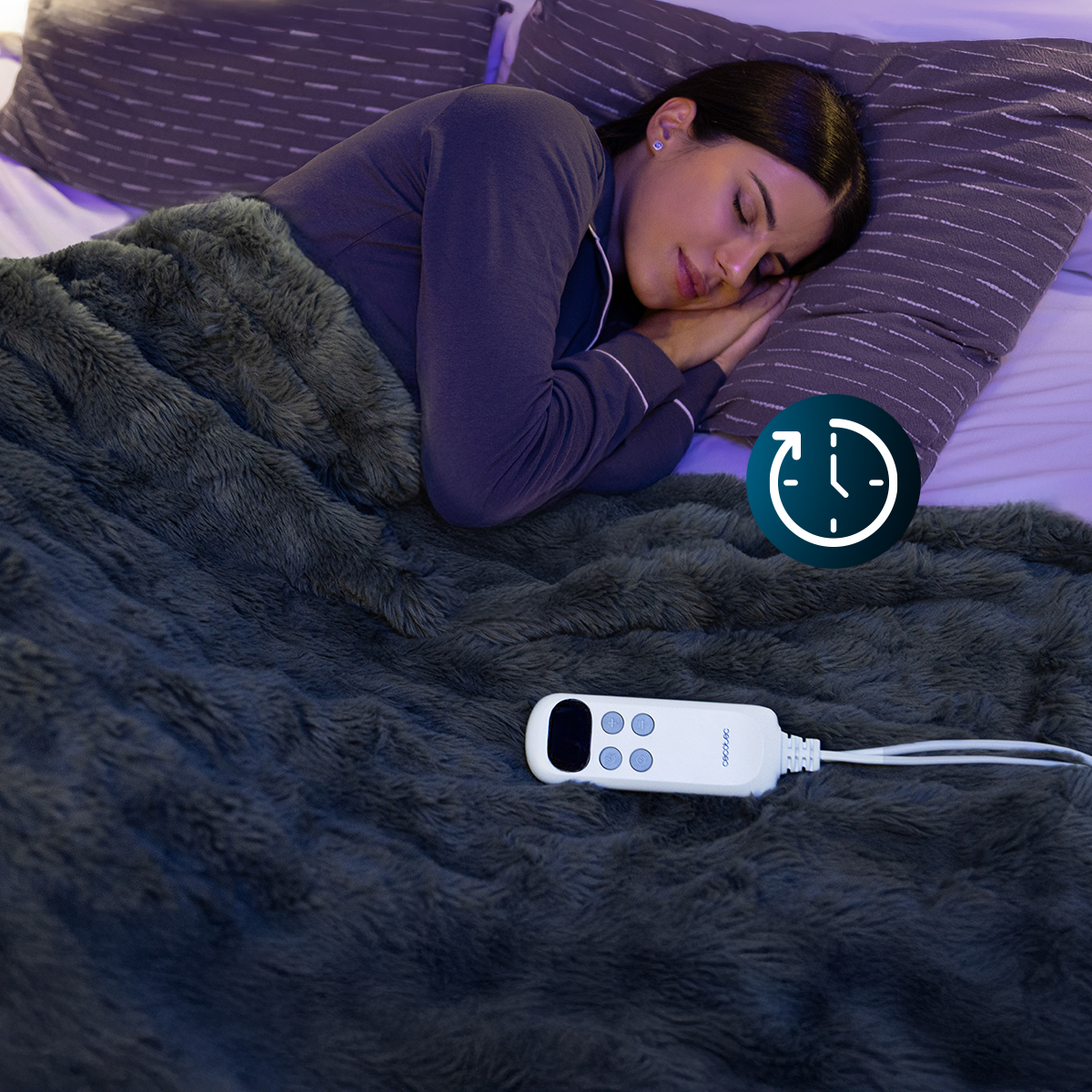 Una mujer duerme bajo una manta gris en una cama. Hay un panel de control y un icono de temporizador en la imagen.