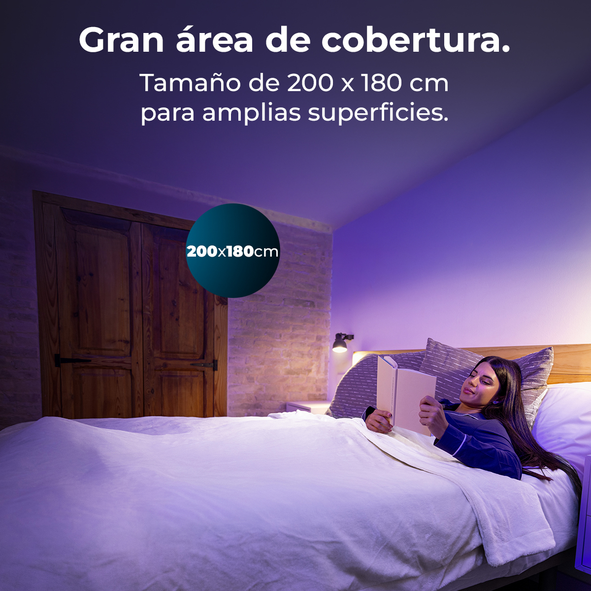 Una mujer lee en la cama. La habitación tiene puertas de madera, paredes de ladrillo y una lámpara. Texto: Gran área de cobertura, 200x180cm.