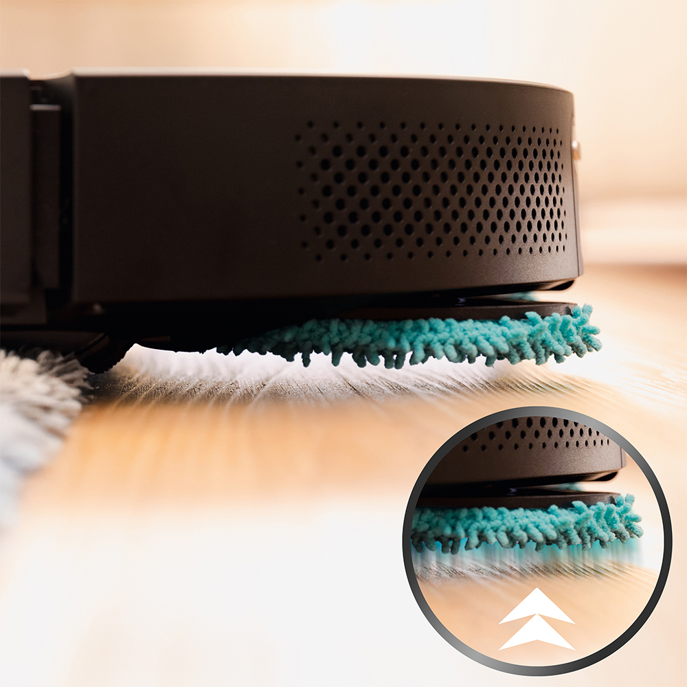 Primer plano de un robot aspirador oscuro con una mopa azul en un suelo de madera. Una incrustación circular muestra la almohadilla y flechas hacia arriba.