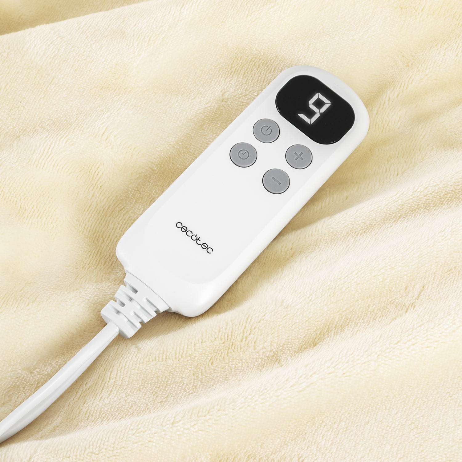 Un mando a distancia blanco con una pantalla digital que muestra el número 9, sobre una suave manta beige. Botones de encendido y ajuste.