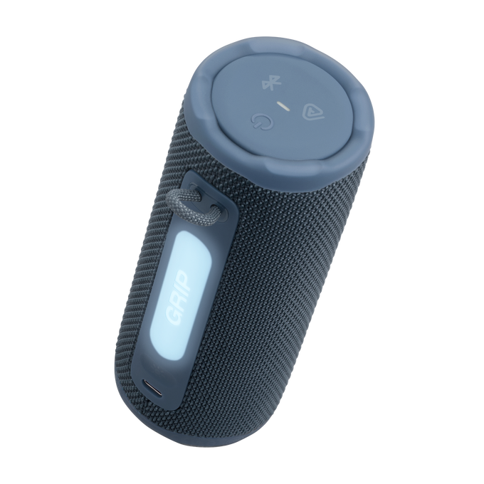 Un altavoz cilíndrico gris oscuro con tapa azul. Tiene un asa con la etiqueta 'GRIP' y botones de control. Un lazo de cable está adjunto.
