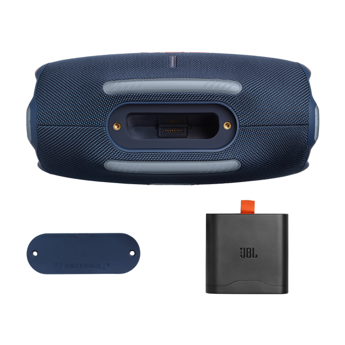 Un altavoz JBL azul oscuro, una pequeña base azul y un adaptador de corriente JBL negro se muestran sobre un fondo oscuro.