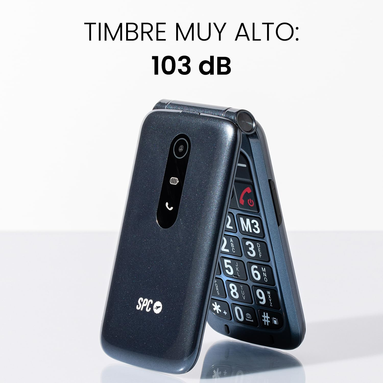 Un teléfono plegable azul oscuro con botones grandes, abierto. Texto superior: 'TIMBRE MUY ALTO: 103 dB'.