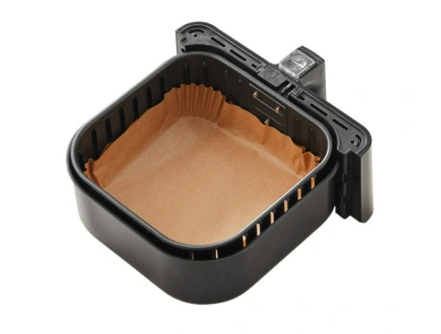 Czarny kosz do frytkownicy powietrznej z brązową papierową wkładką. Kosz jest otwarty i gotowy do użycia, na białym tle.