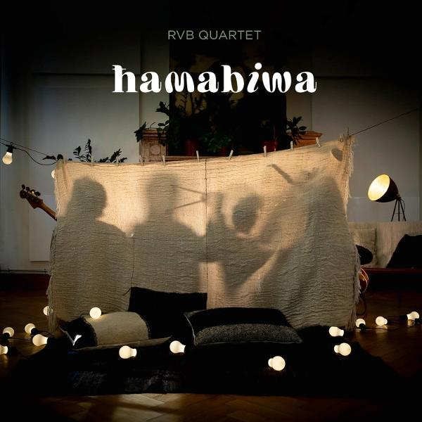Schatten von Personen hinter einem Tuch, mit einer Gitarre. Lichter und Kissen befinden sich im Vordergrund. Das Wort hamabiwa steht oben.
