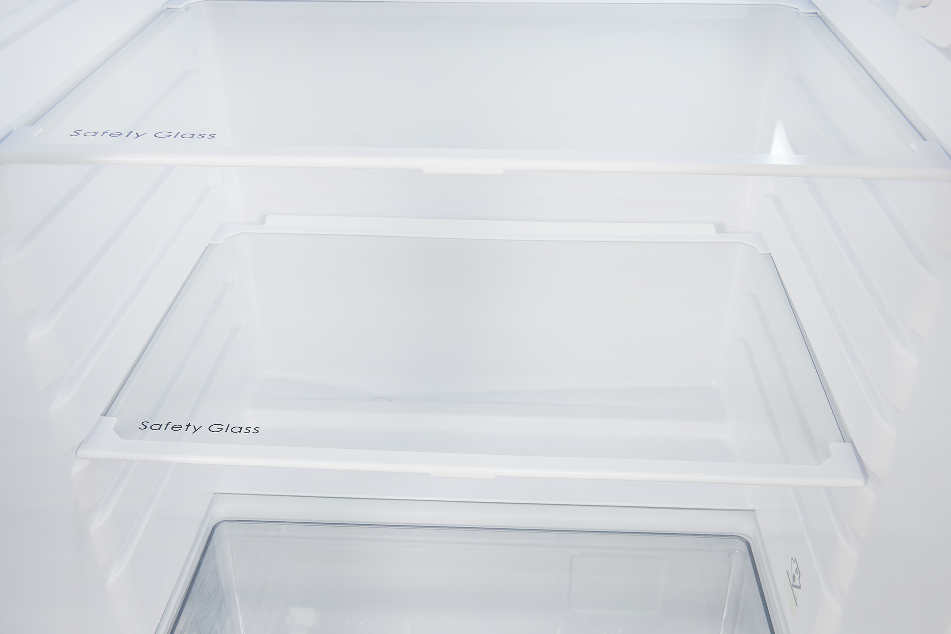 In einem weißen Kühlschrank. Es gibt mehrere Regale, auf denen die Worte "Sicherheitsglas" zu sehen sind. Der Innenraum ist sauber und leer.