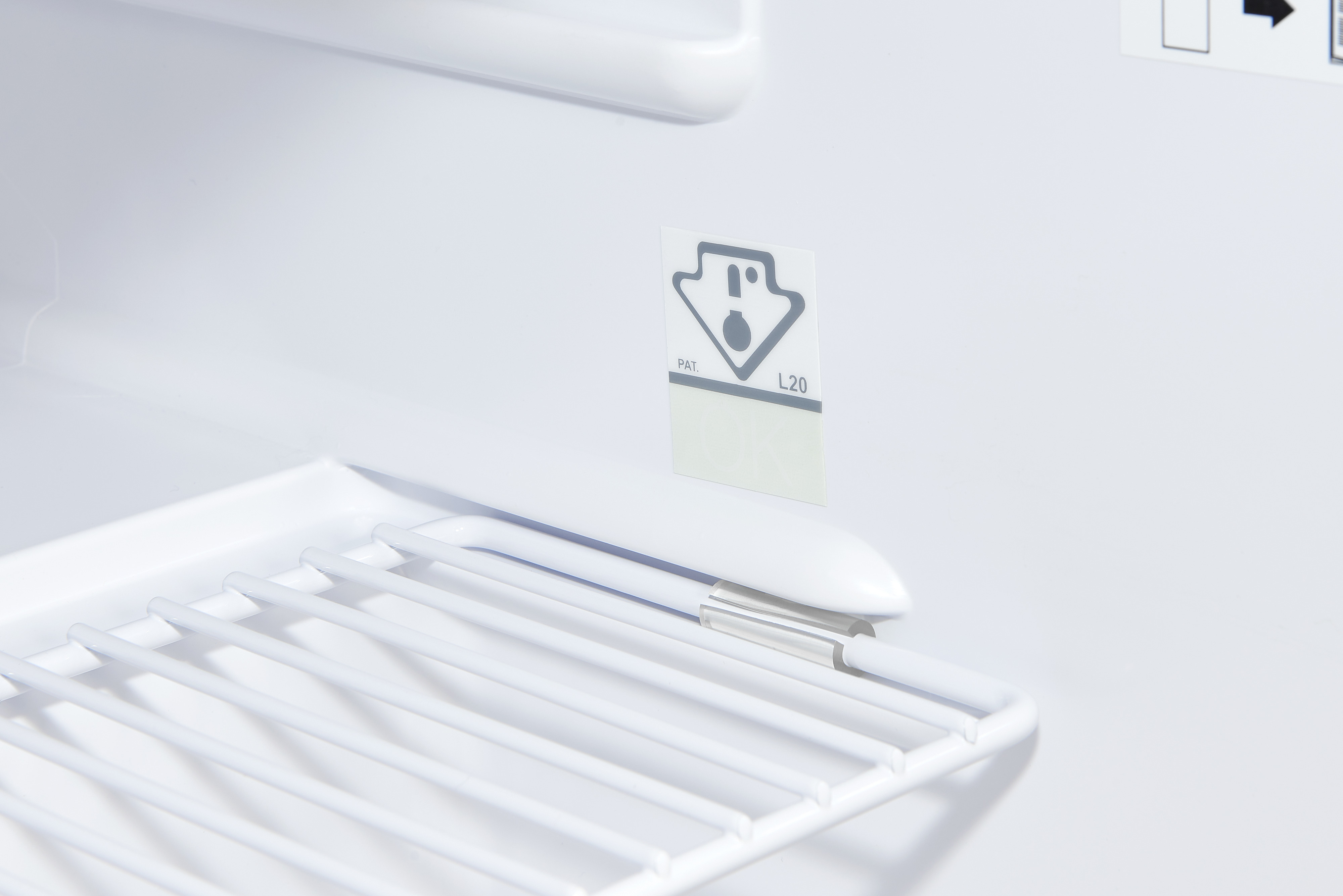 In einem weißen Kühlschrank: ein Metallregal und ein Aufkleber mit einem Diagramm. Die Szene ist sauber und minimalistisch.