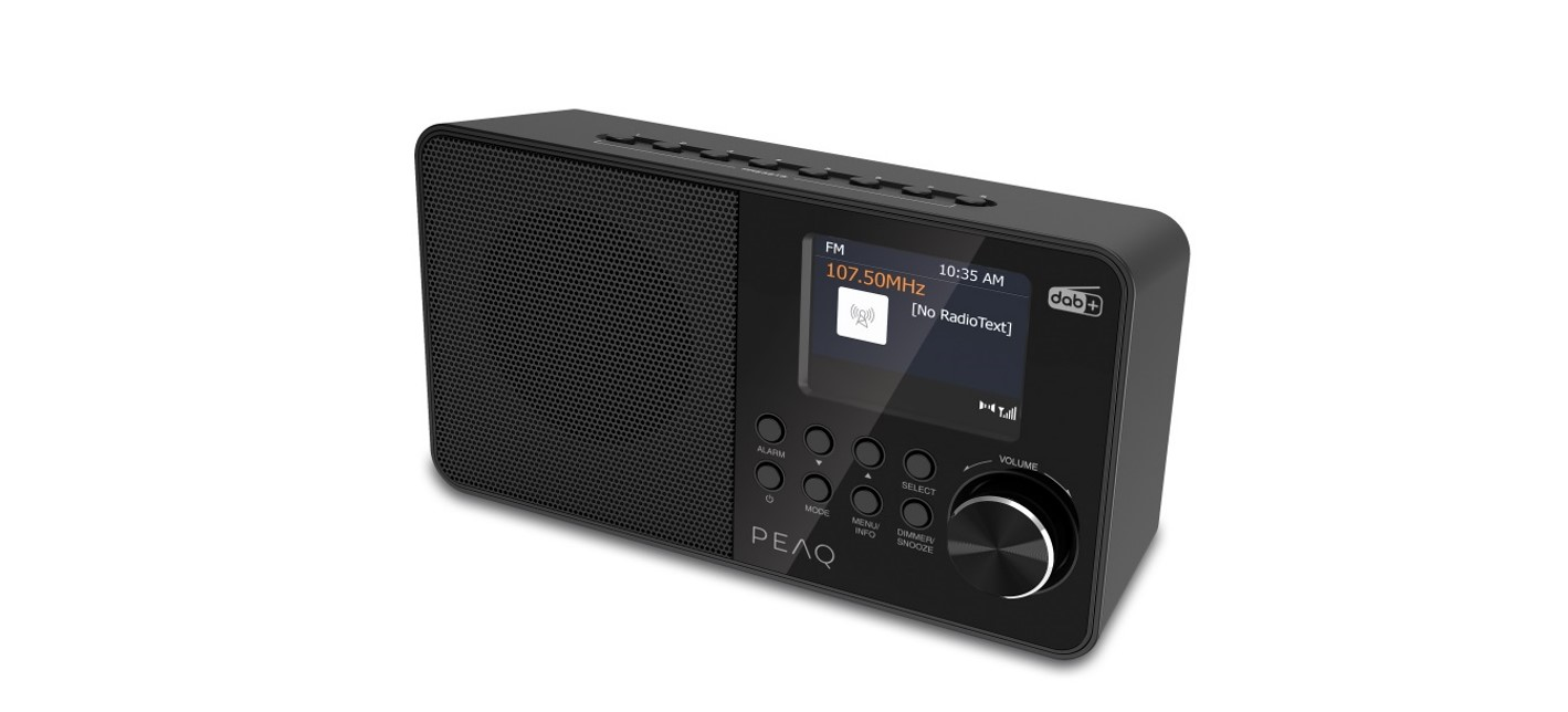 Czarny radioodtwarzacz PEAQ. Wyświetla informacje o radiu FM na ekranie. Elementy sterujące obejmują przyciski alarmu, trybu i pokrętło głośności.