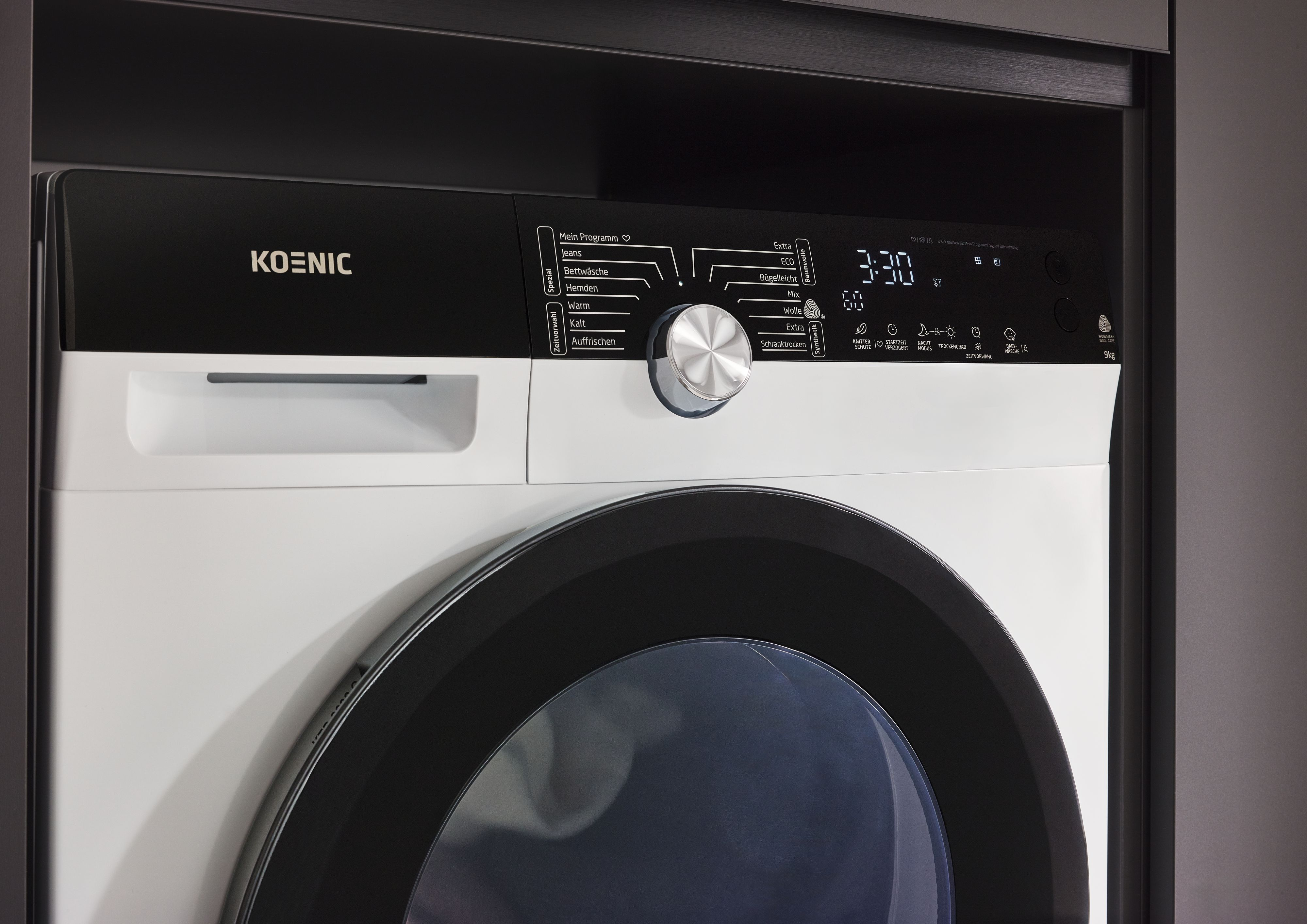 Eine weiß-schwarze Waschmaschine mit Digitalanzeige, Knöpfen und einer großen runden Tür.
