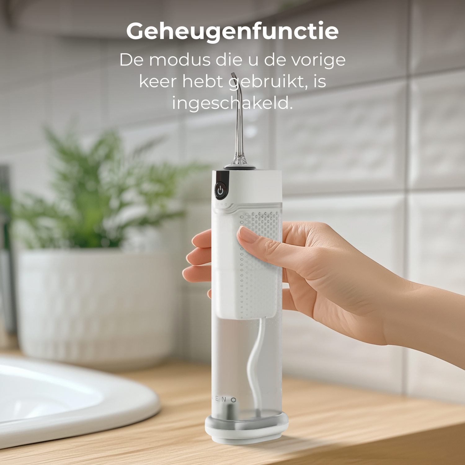 A hand holds a white and transparent oral irrigator. The background shows a sink, tiles, and a potted plant.