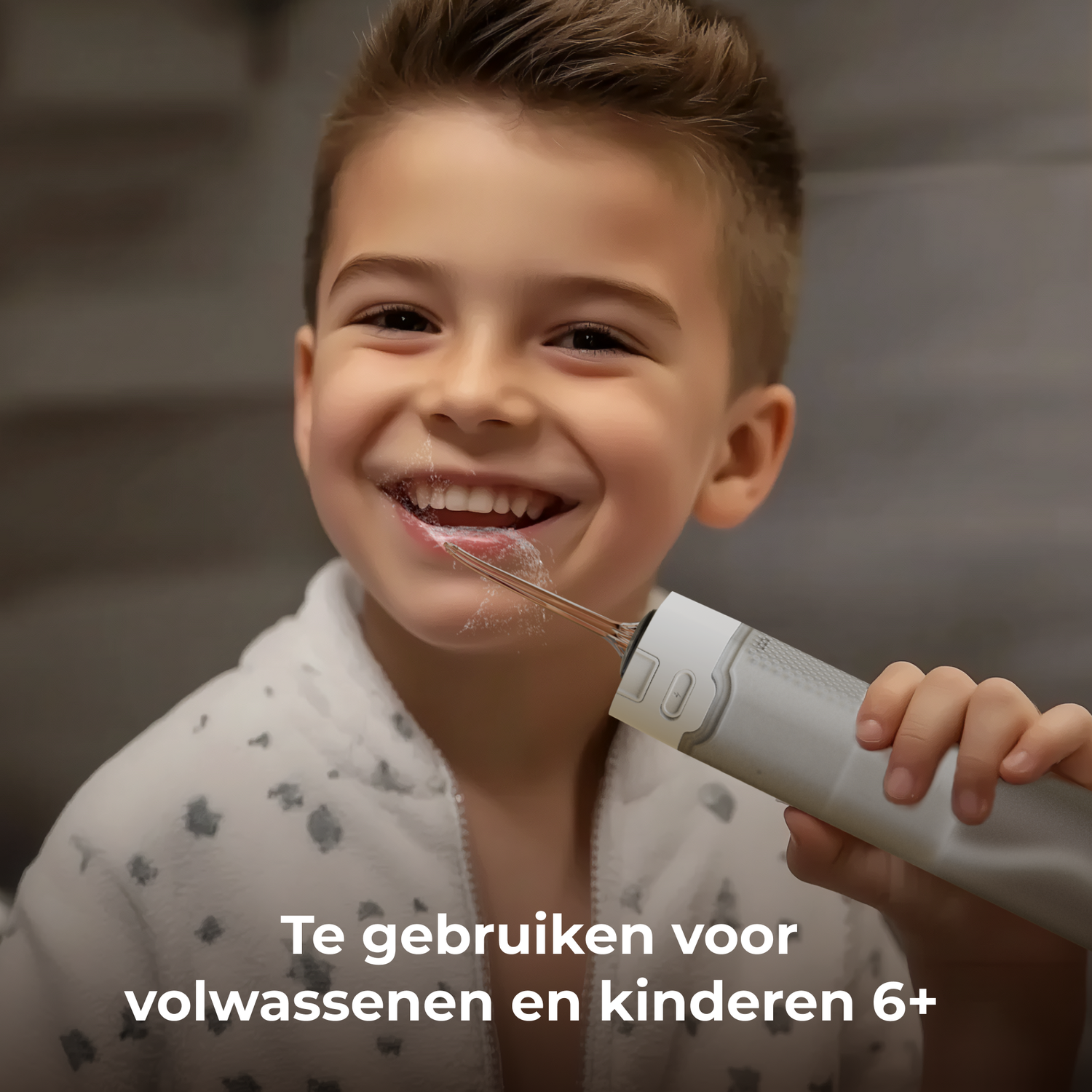A smiling boy uses a dental water flosser. The flosser is white. He is wearing a bathrobe. Text at the bottom says 'To use for adults and children 6+'.