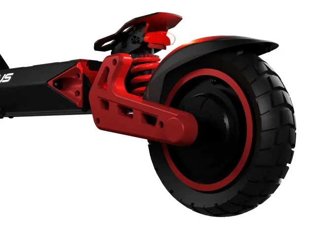 Zbliżenie tylnego koła czarno-czerwonej hulajnogi elektrycznej. Opona jest czarna z czerwonym wykończeniem. Czerwone zawieszenie i elementy ramy.