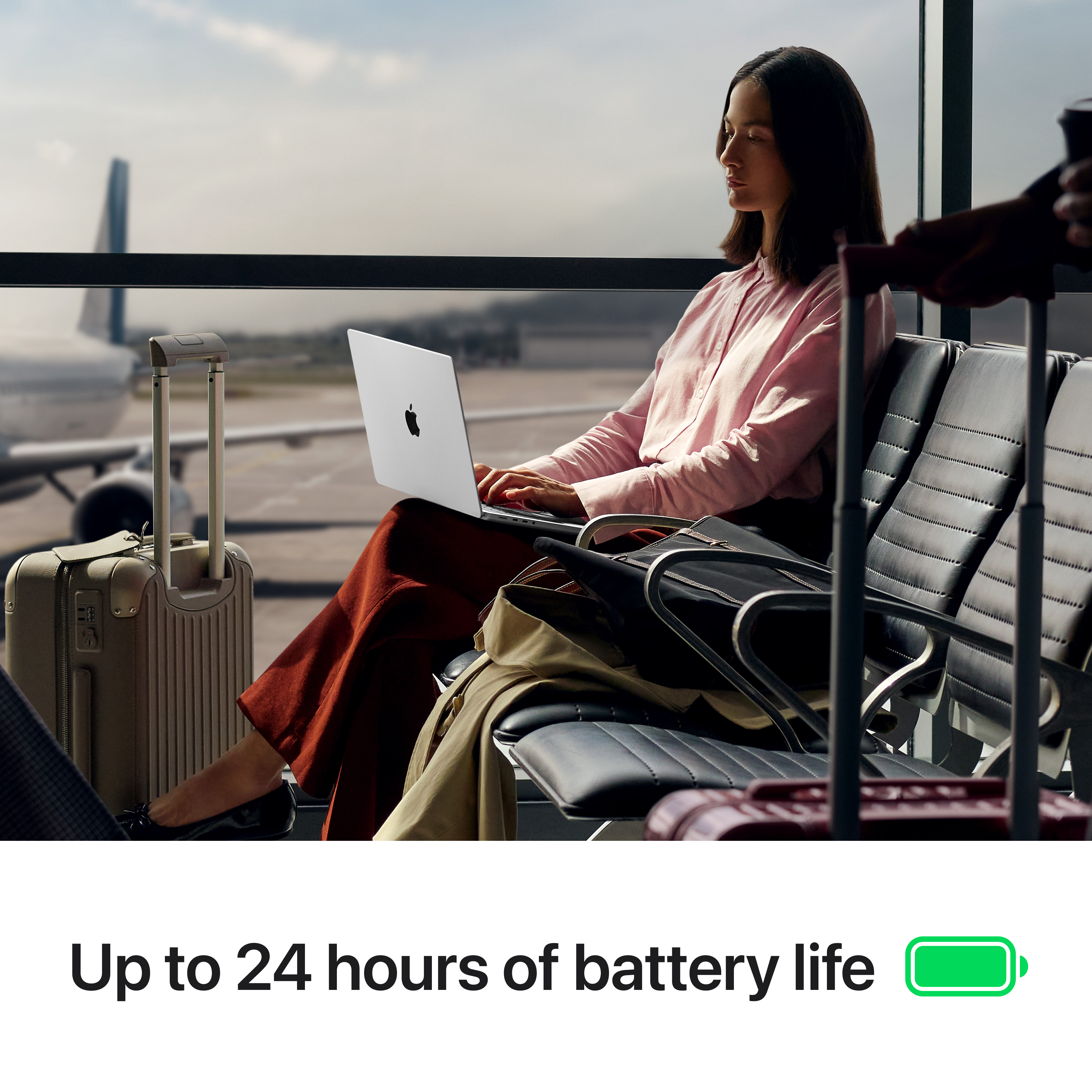 Donna usa laptop in aeroporto. Bagagli e aereo visibili. L'immagine promuove la durata della batteria.