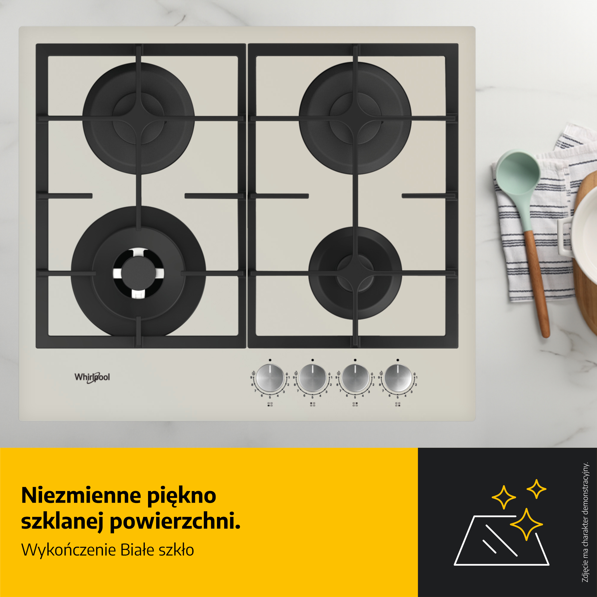 Biała szklana płyta grzewcza z czterema czarnymi palnikami i pokrętłami. Po prawej stronie chochla, miska i ściereczka.