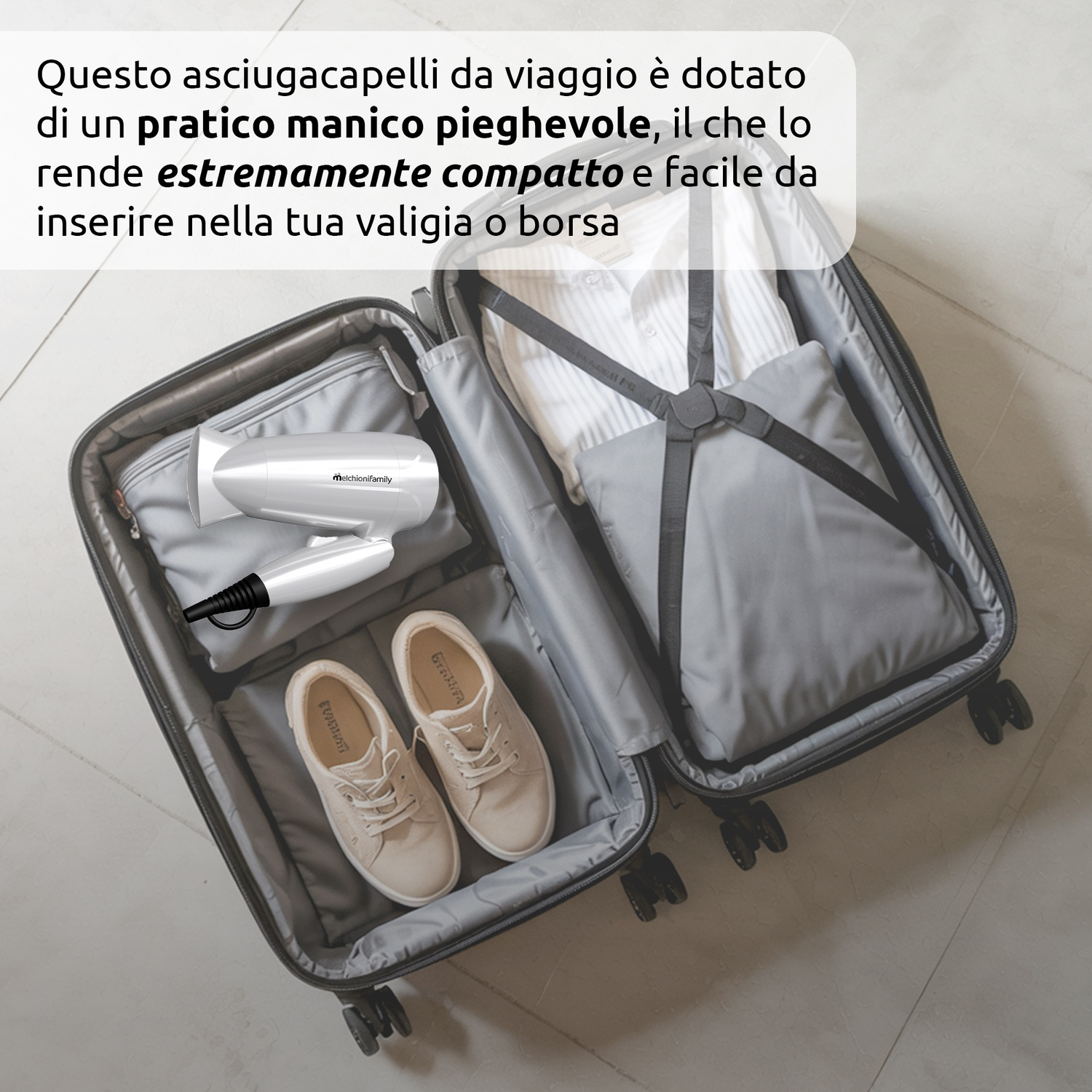 Valigia aperta con vestiti, scarpe e asciugacapelli pieghevole. La valigia è grigia su un pavimento grigio chiaro.