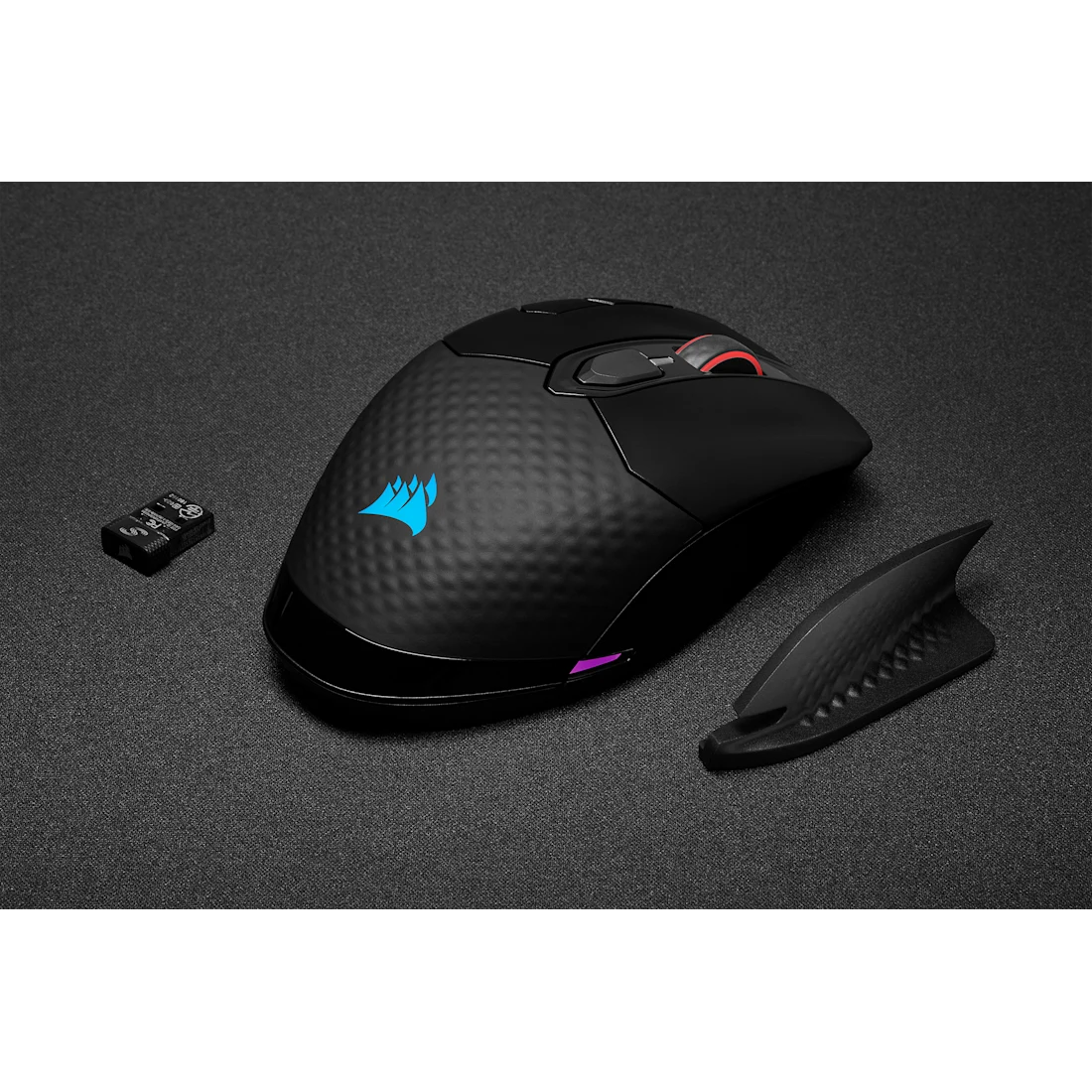 Fekete Corsair gaming egér levehető szárnnyal és USB vevővel texturált fekete felületen. Kék logó és piros görgetőkerék.