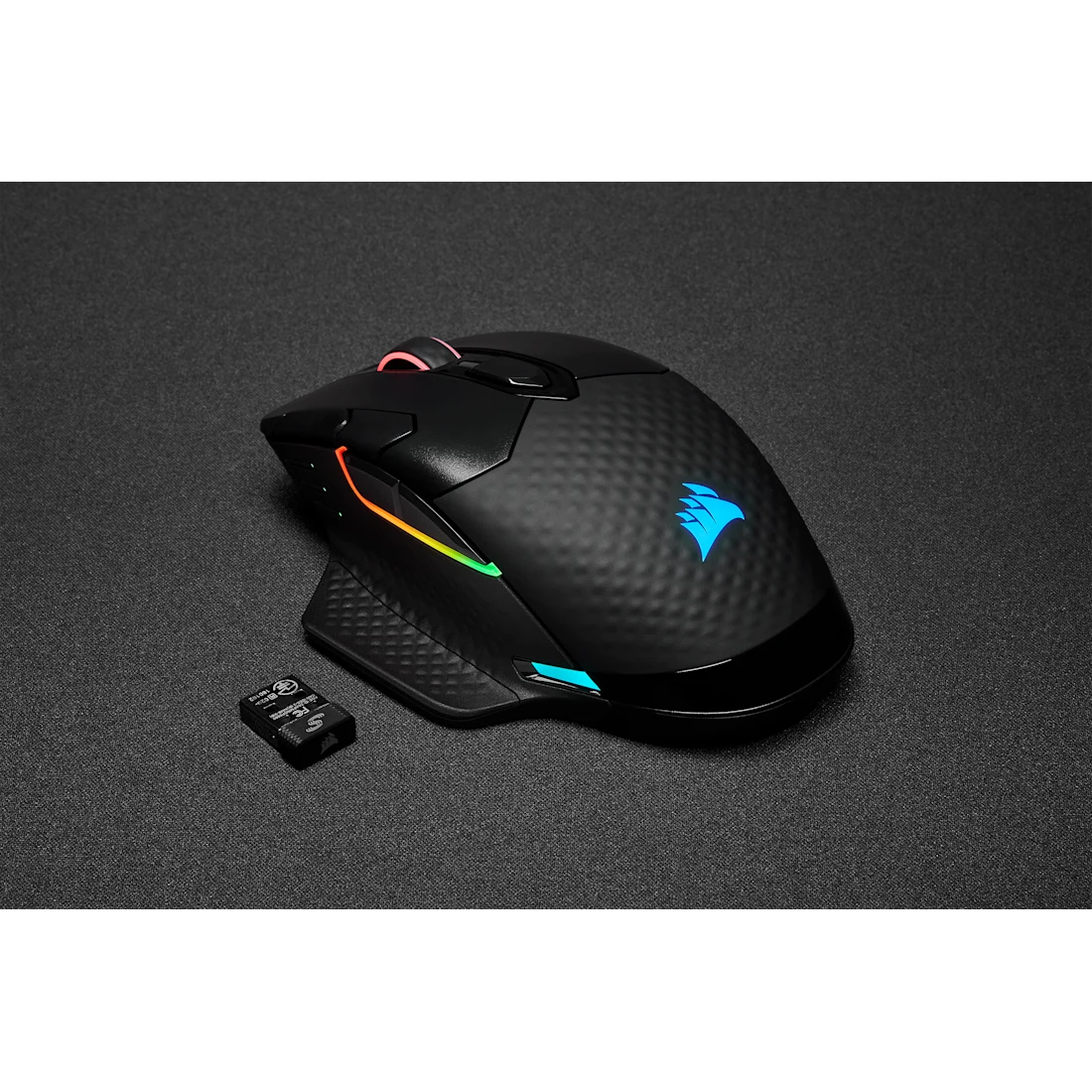 Fekete Corsair gamer egér RGB-világítással és vezeték nélküli vevővel fekete felületen.
