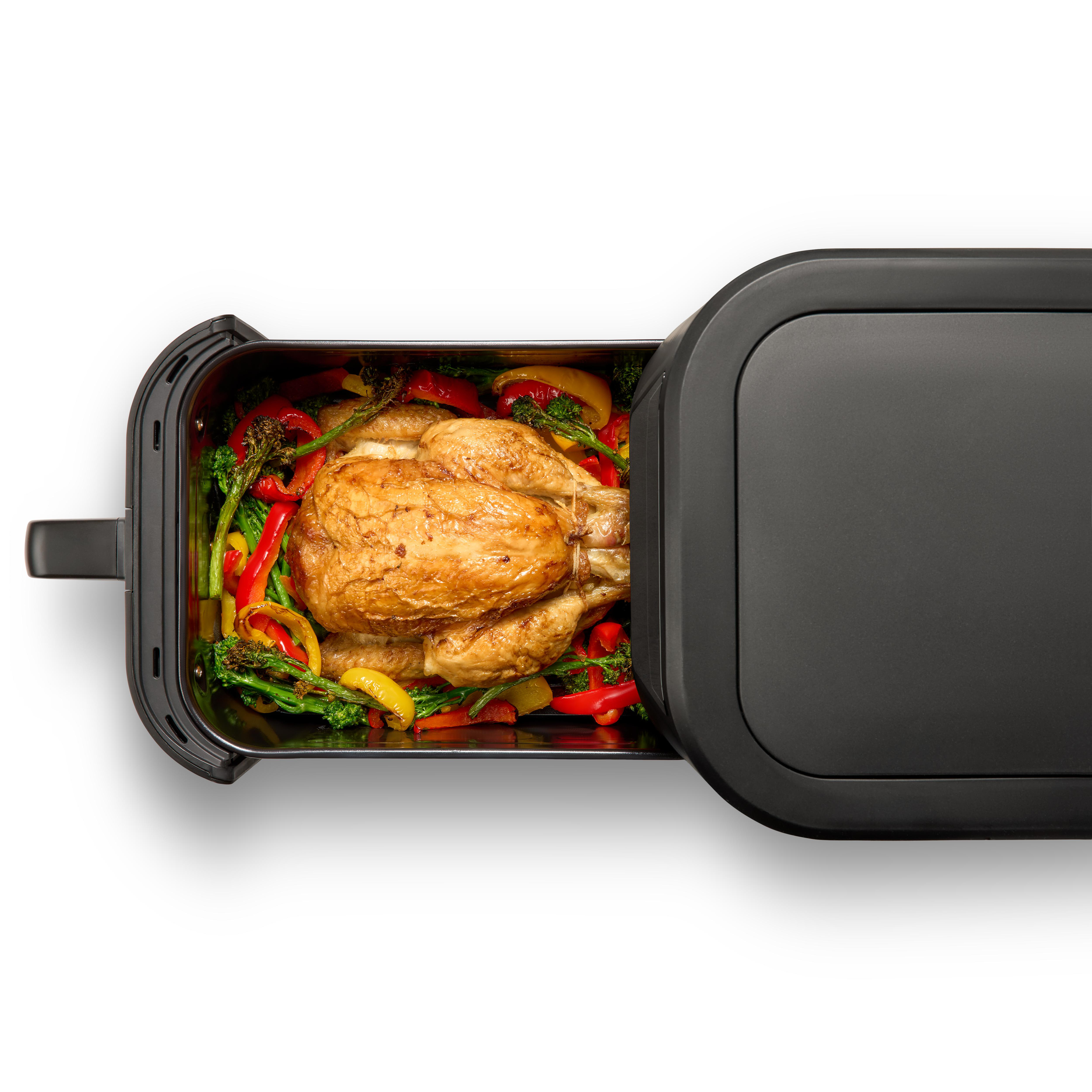 Gebratenes Hähnchen und Gemüse in einem schwarzen Ofen. Paprika und Brokkoli umgeben das Huhn.