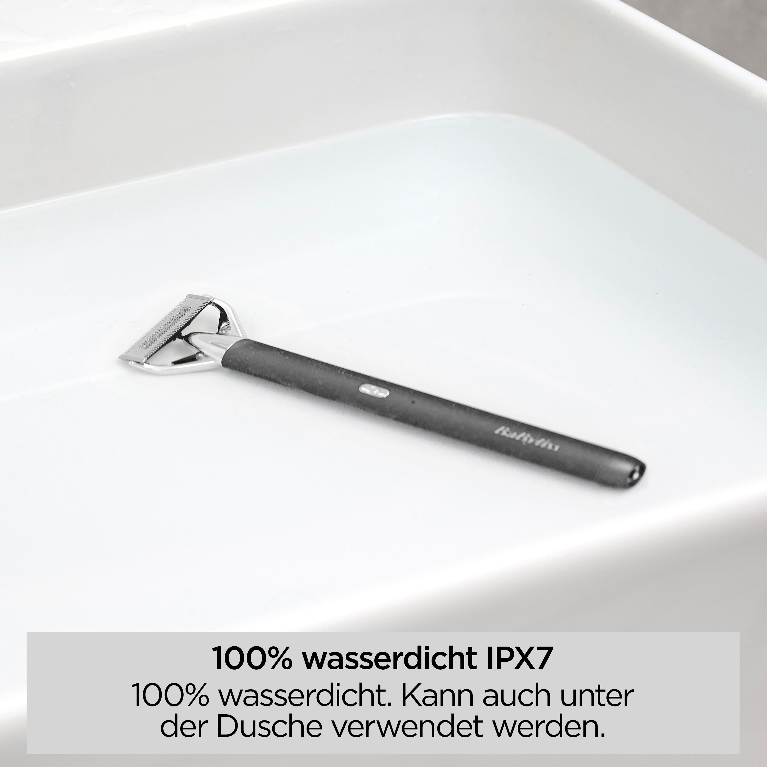 Ein schwarzer und silberner Rasierer ist in Wasser in einem weißen Waschbecken getaucht.