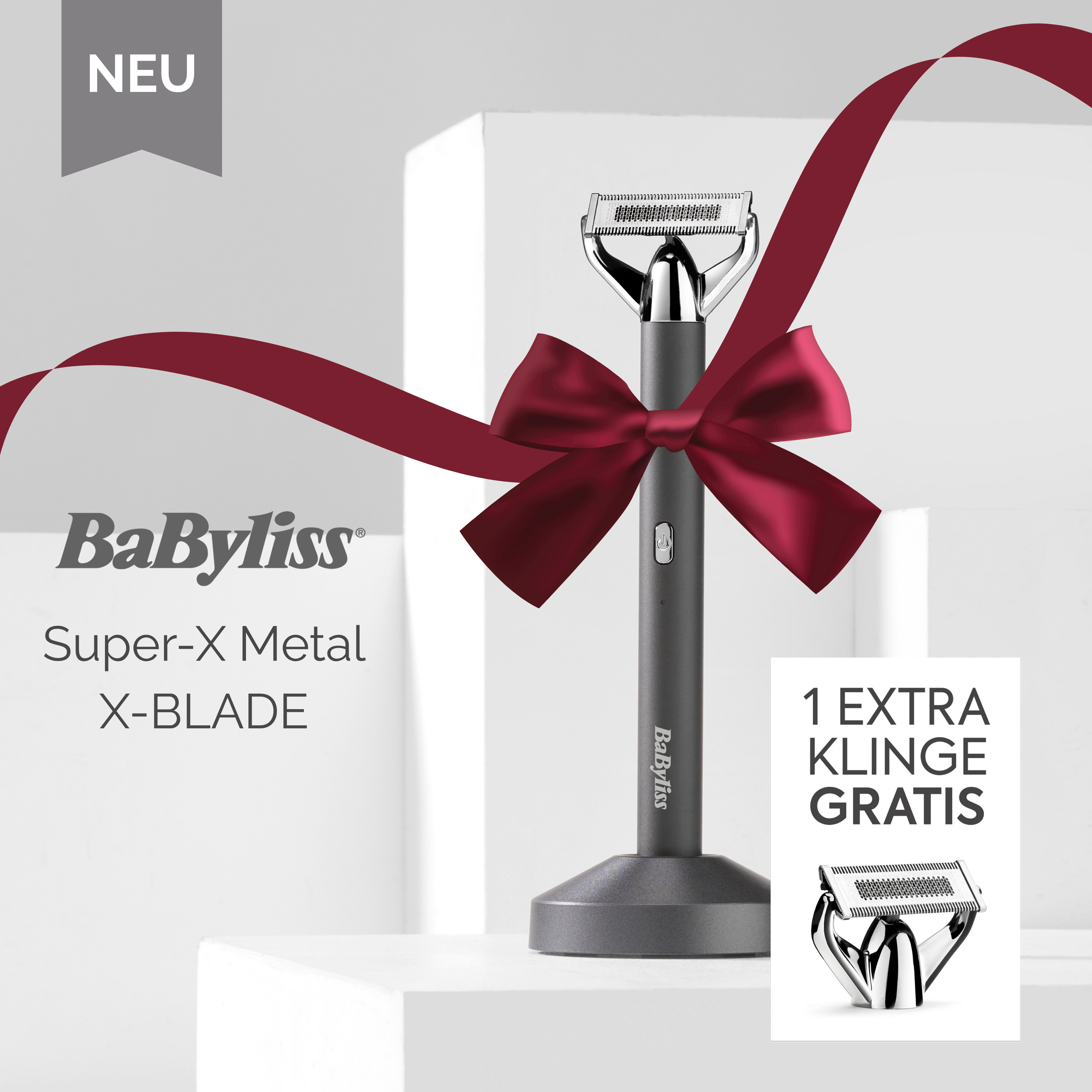 Ein Babyliss Super-X Metal X-BLADE Rasierer wird mit einem roten Band präsentiert. Eine kostenlose Ersatzklinge ist enthalten.