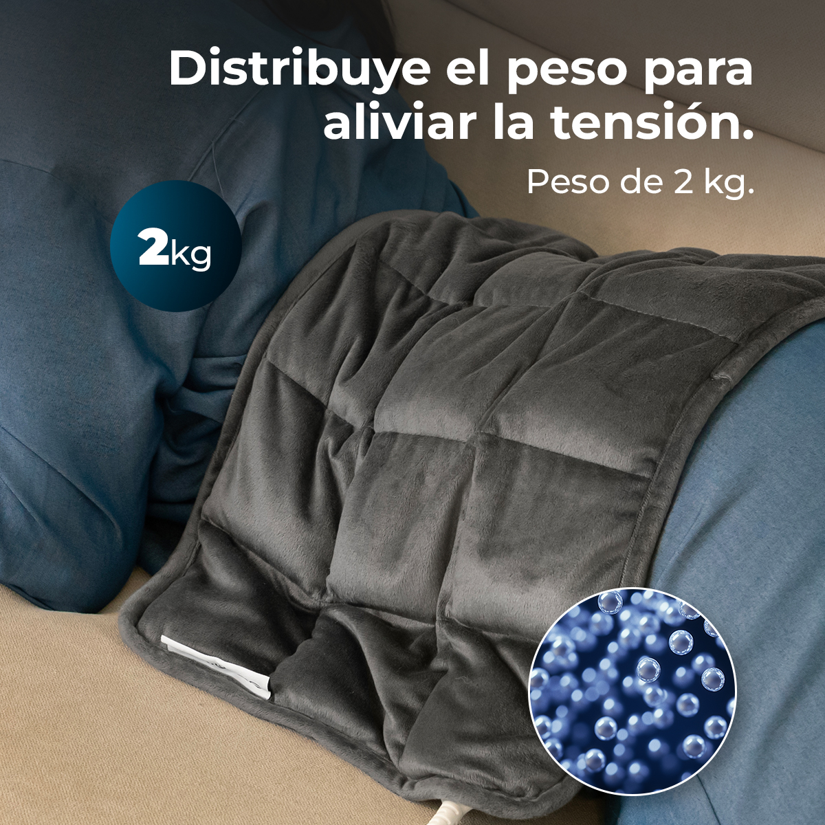 Una persona está cubierta con una manta pesada gris sobre un sofá beige. El texto dice: 'Distribuye el peso para aliviar la tensión. Peso de 2 kg'.