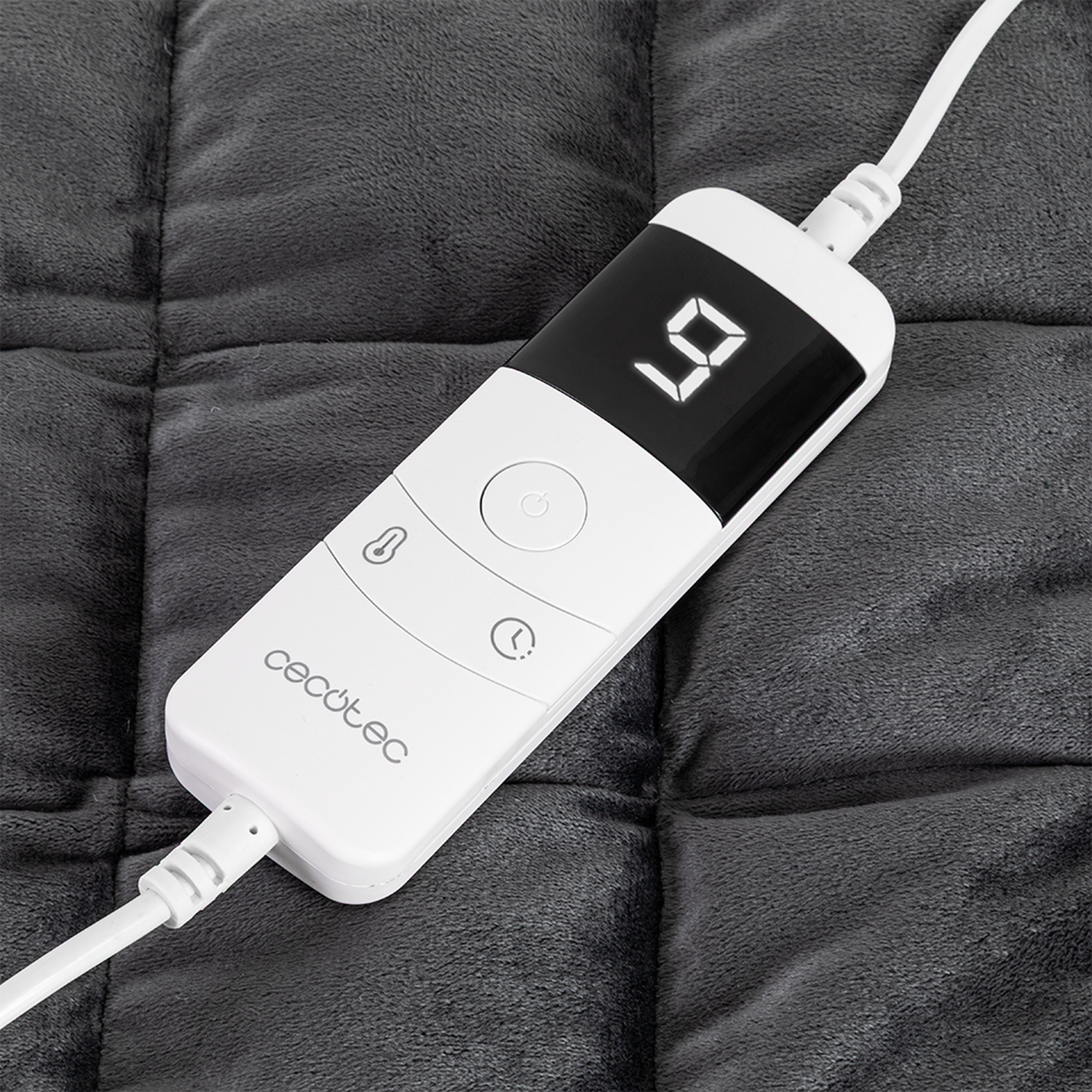 Un controlador Cecotec blanco muestra '9' en una almohadilla térmica acolchada gris oscuro. Los cables conectan el controlador.