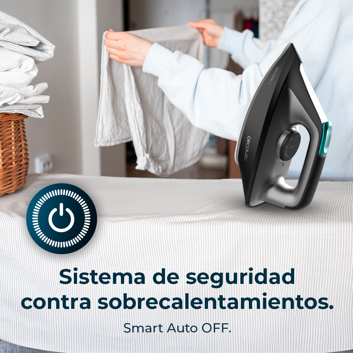 Una persona plancha ropa con una plancha negra sobre una tabla de planchar. A la izquierda, una cesta de ropa doblada.